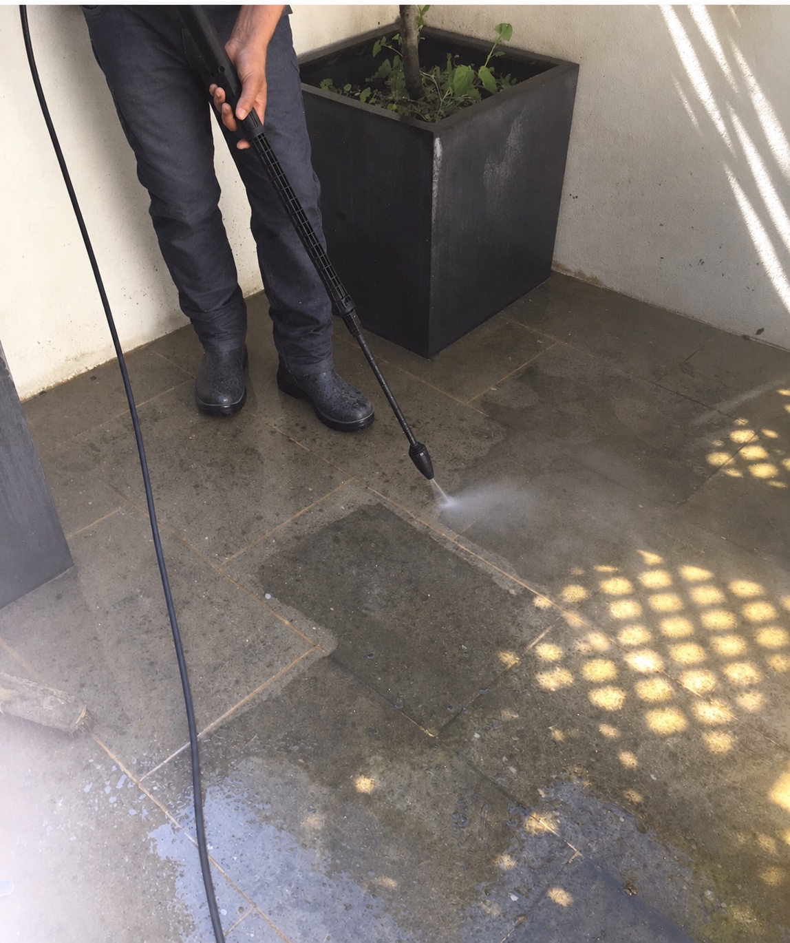 A patio halfway through a pressure wash, clean and dirty stone side by side