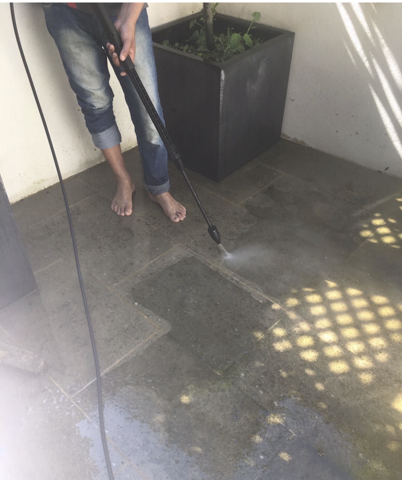 A terrace being pressure washed next to a large planter