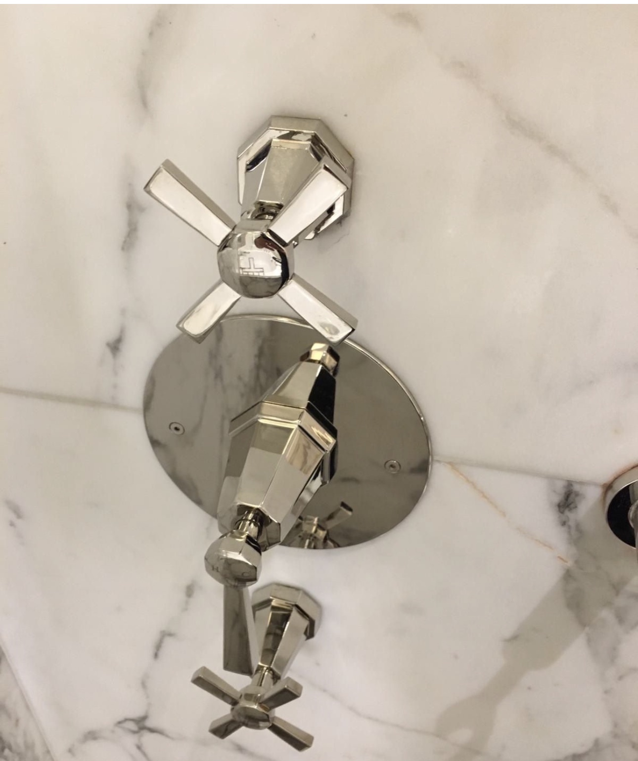 Close-up of polished cross-head taps on white marble
